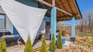 Un espace extérieur abrité doté d’une terrasse en bois, d’une piscine et de plusieurs plantes en pot.