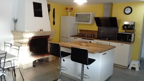 A compact kitchen with a central island, a microwave, a coffee maker, and a clock on the wall. - Vacation home in Meschers quiet area (Meschers-sur-Gironde)