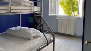 A dormitory room with bunk beds, a radiator, a window with a view of trees, and a hanging light fixture. - Vacation home in Meschers quiet area (Meschers-sur-Gironde)