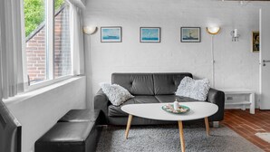 A modern living room with a grey sofa, a round white coffee table, and a brick wall. - 2 bedroom lovely home in Rømø (Rømø)