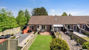 A two-story house with a tiled roof, a fenced backyard, and outdoor seating areas. - 2 bedroom lovely home in Rømø (Rømø)