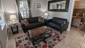 Ein Wohnzimmer mit zwei schwarzen Ledersofas, einem Holztisch und einem gemusterten Teppich.