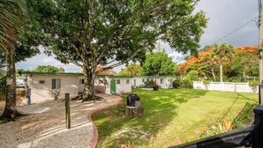 Ein Wohngebiet mit Rasengrundstück, Grillplatz und einer kleinen Gartenhütte.