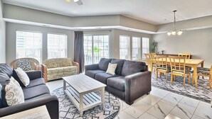 Un salon spacieux comprenant un canapé, un fauteuil, une table basse et un coin repas avec une table et des chaises.