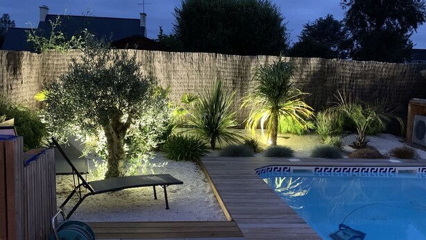 Ein Garten mit Schwimmbad, einer Holzterrasse und einem Gartenschlauchaufroller.