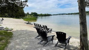 Una zona sul lago con diverse sedie Adirondack disposte su un sentiero sterrato.