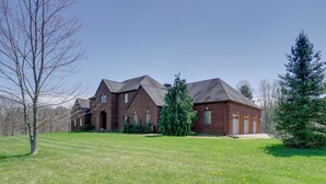 A large brick house with a spacious lawn and a large tree in the foreground.