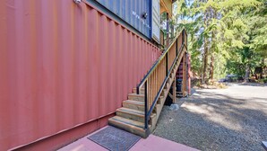 Eine Treppe führt zu einem Gebäude mit roter und blauer Fassade, umgeben von Bäumen.