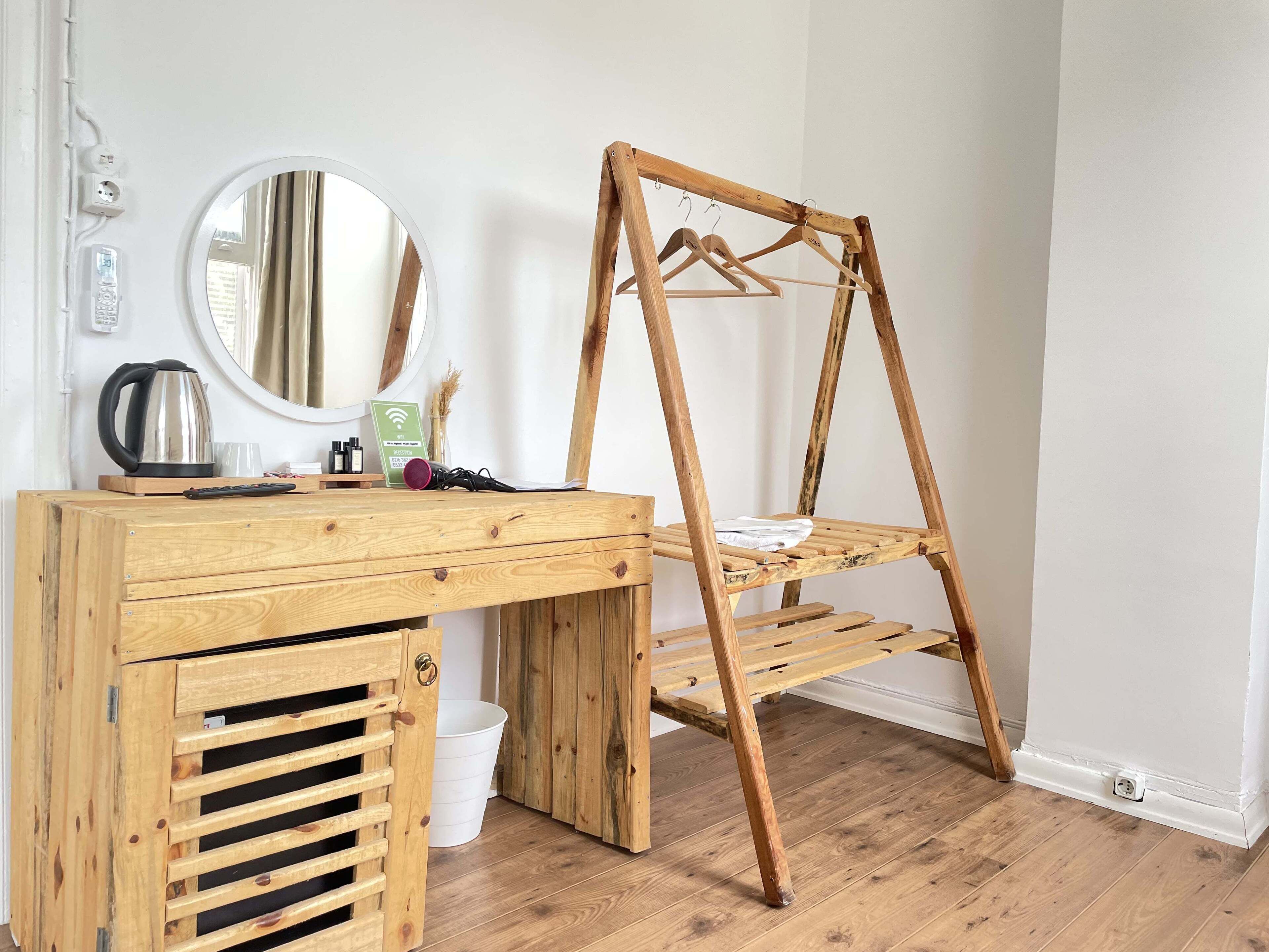 A wooden desk with a mirror, a kettle, and a sign indicating Wi-Fi availability.