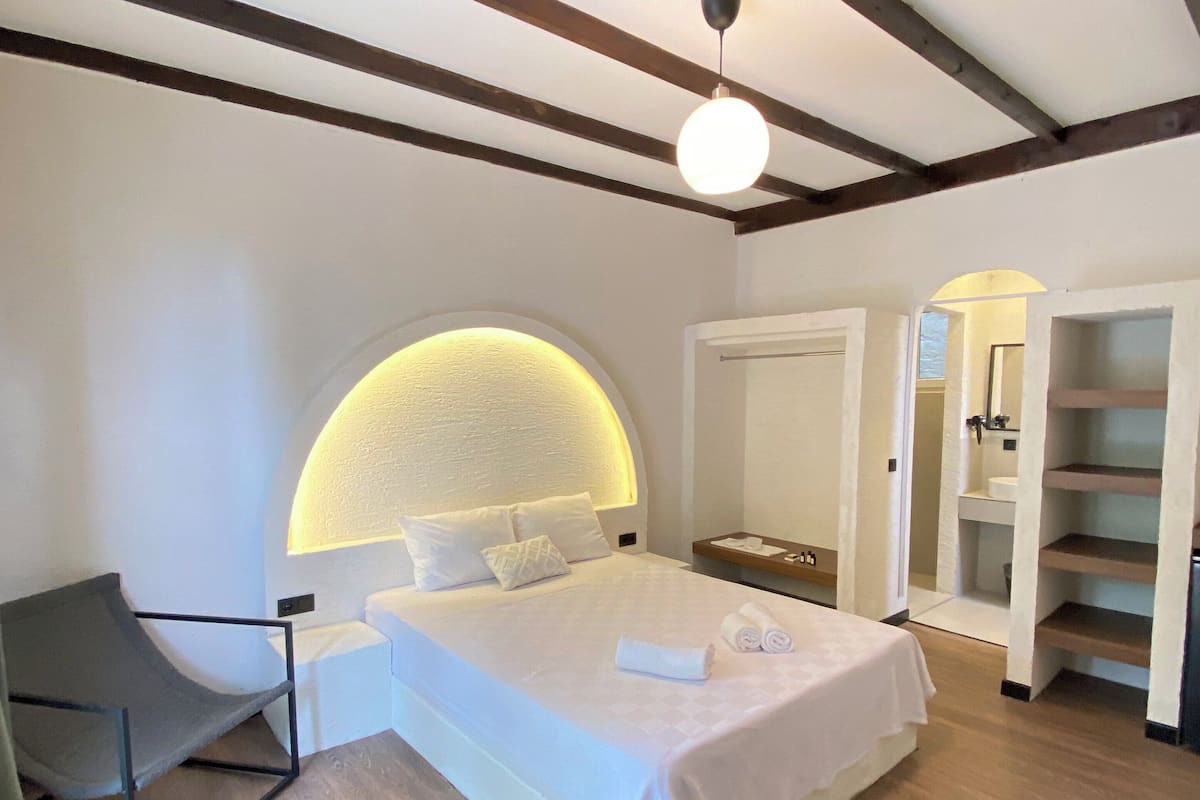A bedroom with a bed, a chair, a bedside table, and a wardrobe.