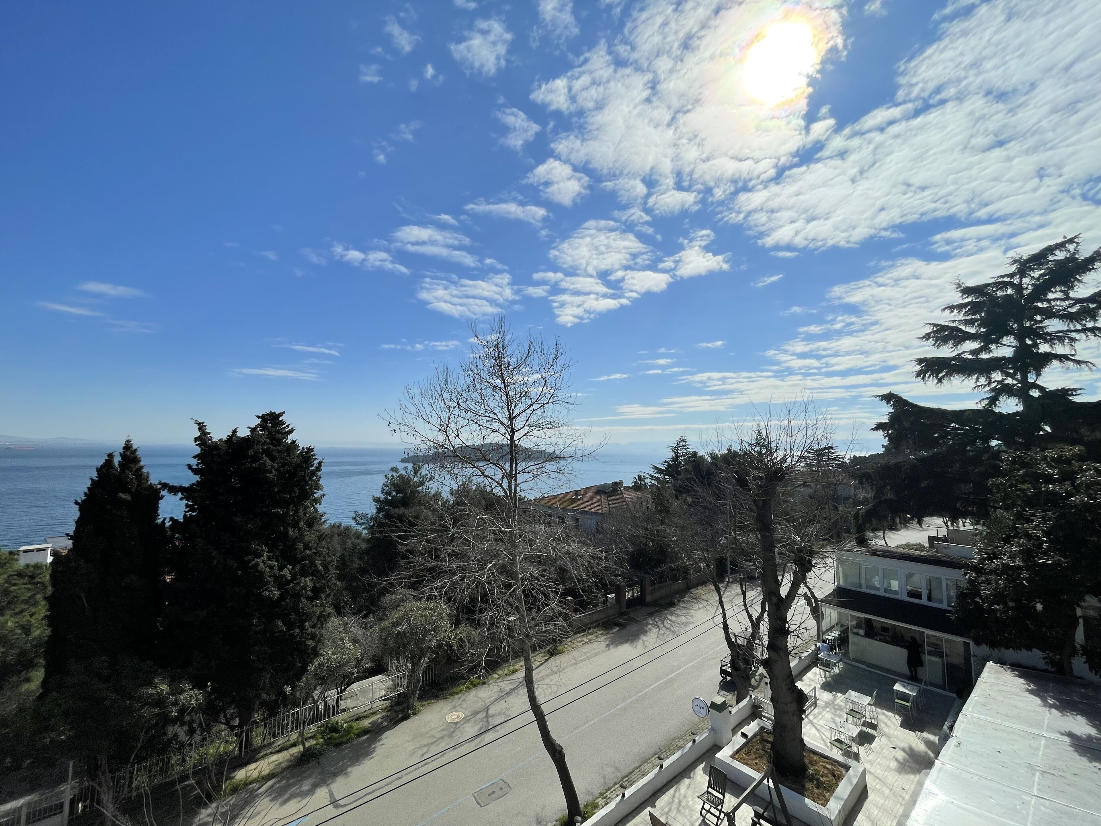 A coastal view with a clear sky, a road, and a building with a balcony.
