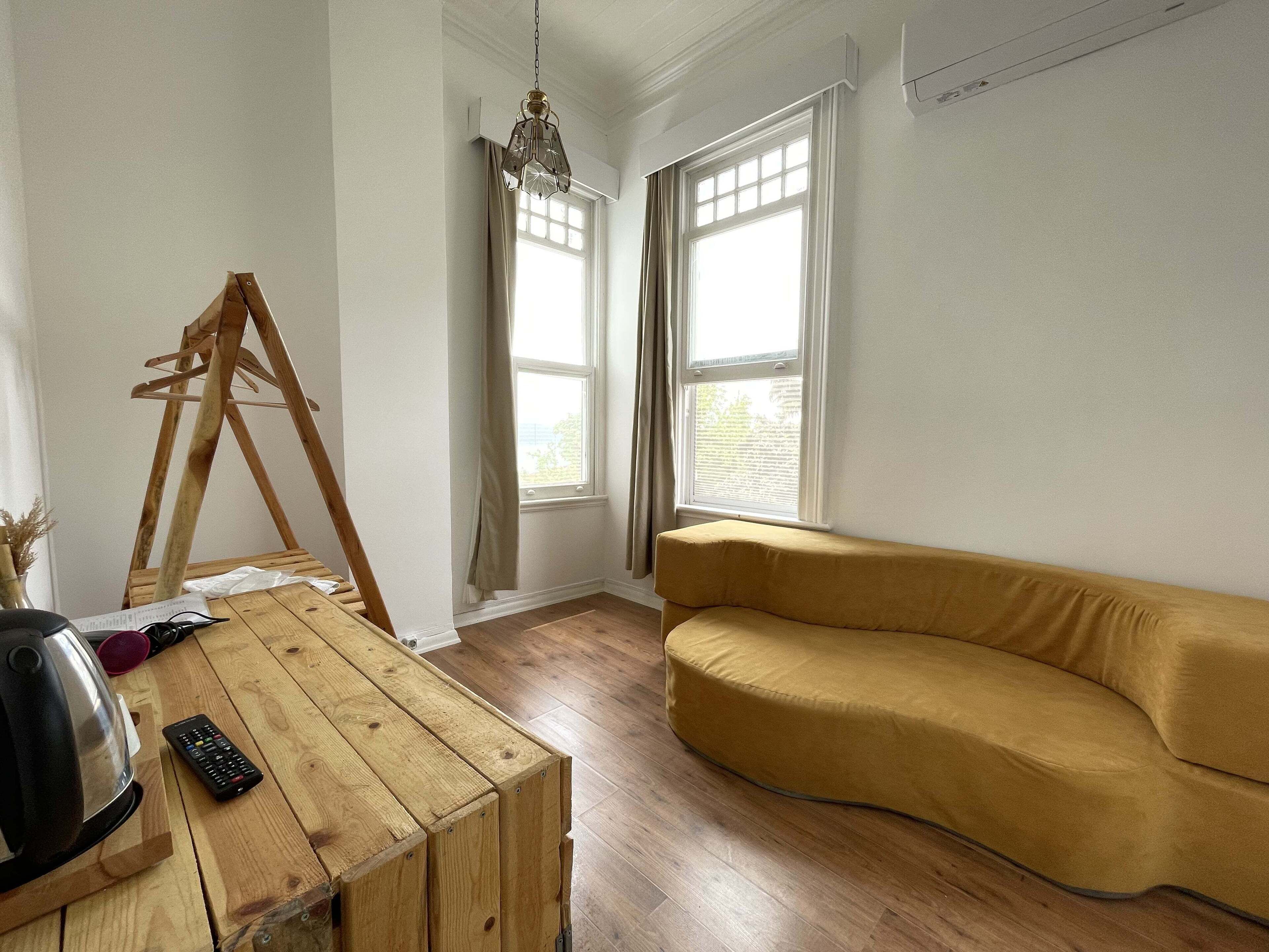 A room with a wooden table, a yellow sofa, and a wooden easel.