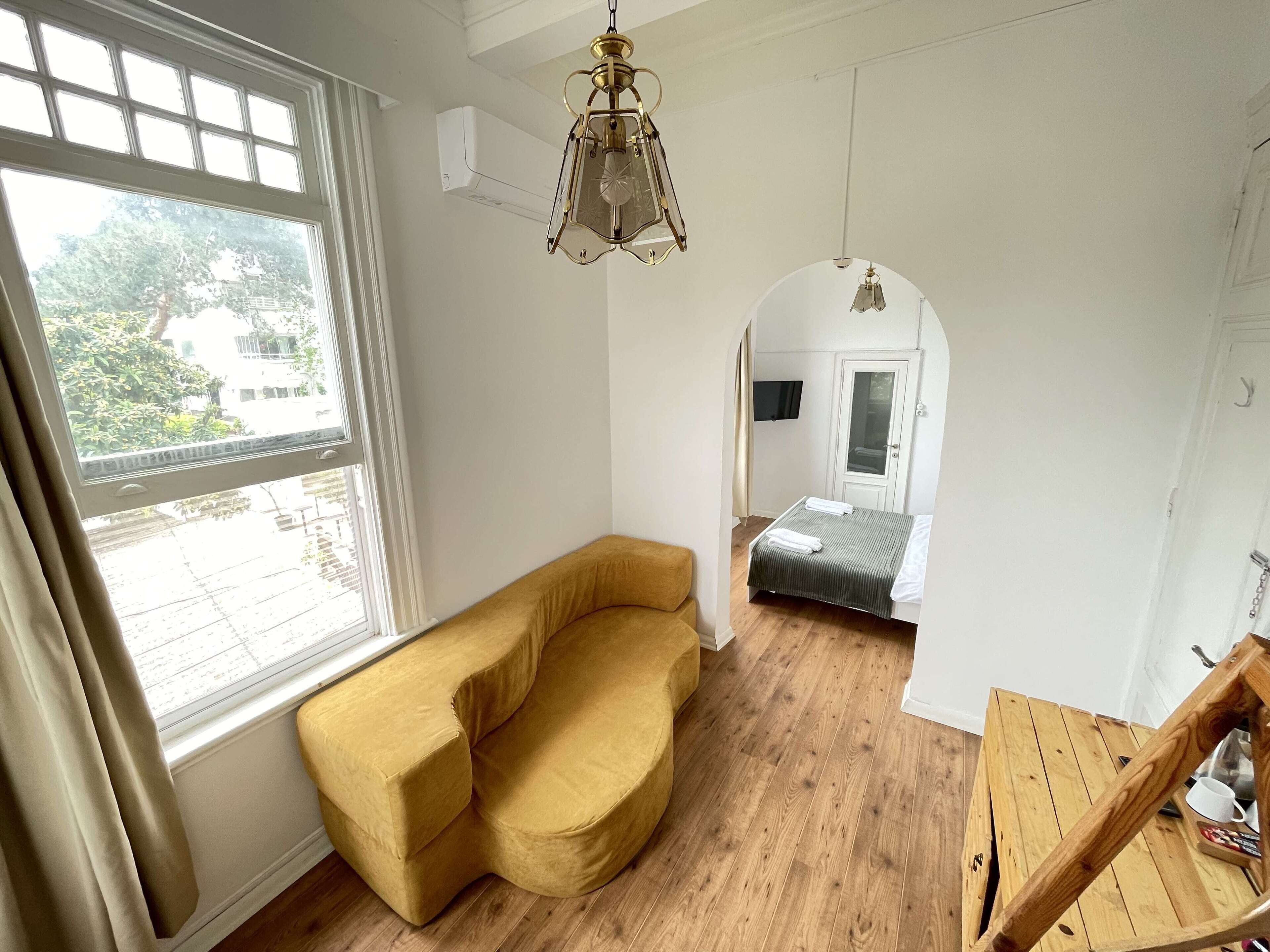 Una habitación con sofá, cama, mesa de madera y lámpara colgante.