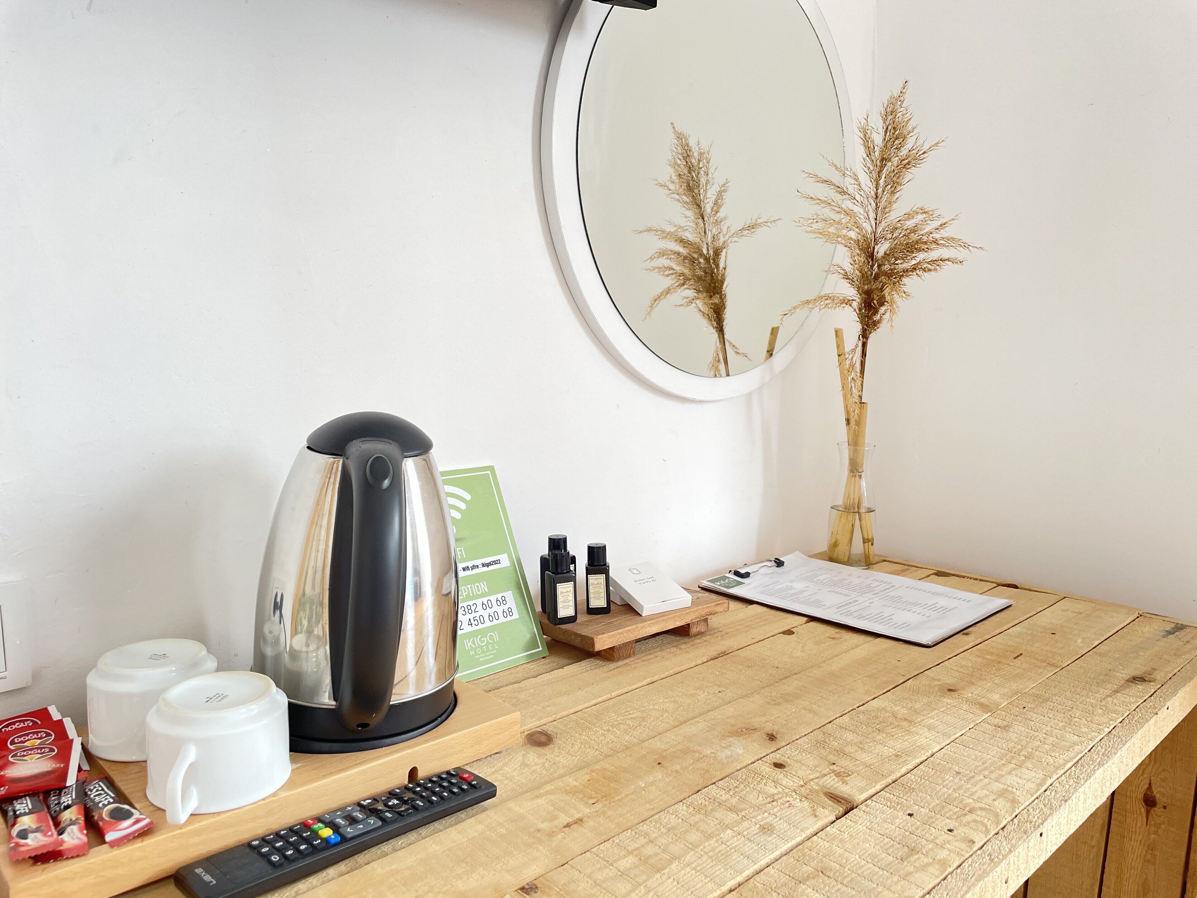 A wooden desk with a kettle, a remote control, and a receipt.