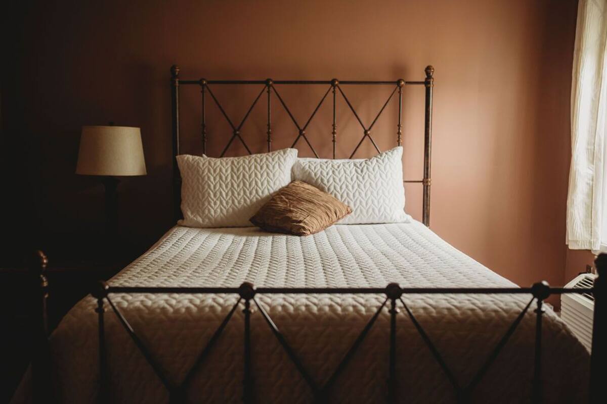 A bed with a metal frame, a quilted mattress, and two pillows.