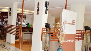 A hotel lobby with a reception desk, a bar area with bottles, and a decorative sculpture.