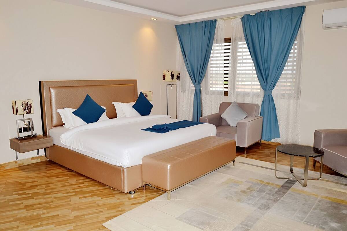A modern hotel room with a large bed, a seating area, and a small table.