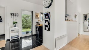 A modern interior with a black and white color scheme, a large wall clock, a door leading to a garden, and a small shelf with decorative items. - Amazing home in Brovst with kitchen (Brovst)