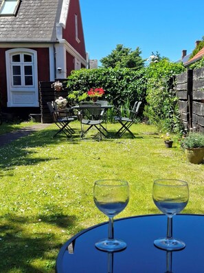 Un patio con una mesa y sillas, una casa al fondo y un jardín.