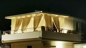 A building with a balcony, covered by beige curtains, and a railing. - Lovely home in Kaukana with WiFi (Kaukana)
