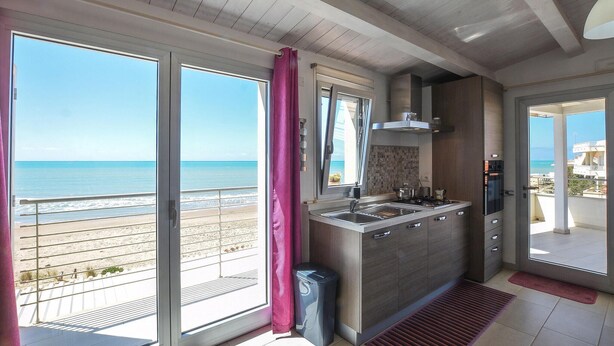 A kitchen with a view of the beach, a gas stove, a sink, and a trash bin. - Lovely home in Kaukana with WiFi (Kaukana)