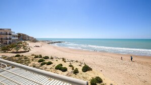 A beach with buildings in the background, a clear sky, and a few people on the sand. - Lovely home in Kaukana with WiFi (Kaukana)