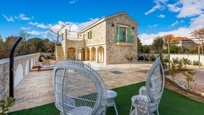 Un bâtiment en pierre doté d’un balcon, de deux fauteuils en osier et d’un petit jardin.
