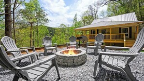 A cabin with a stone fire pit and Adirondack chairs. - Private Cabin • Hot Tub • Relaxing Smoky Getaway (Sevierville)