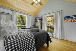 Een slaapkamer met een bed, een televisie en een schilderij aan de muur.