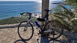 Een fiets geparkeerd langs een kustpad, met uitzicht op zee en strand.