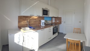 A compact kitchen with white cabinets, a wooden countertop, a microwave, a coffee maker, and a small refrigerator. - Vacation home in a quiet location with field view near Lake Leppinsee (Mirow OT Qualzow)
