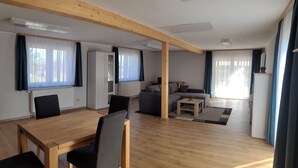 A modern living room with a wooden dining table, black chairs, a grey sofa, and a small coffee table. - Vacation home in a quiet location with field view near Lake Leppinsee (Mirow OT Qualzow)