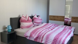 A bedroom with a bed, pillows, a nightstand, a lamp, and a mirror. - Vacation home in a quiet location with field view near Lake Leppinsee (Mirow OT Qualzow)