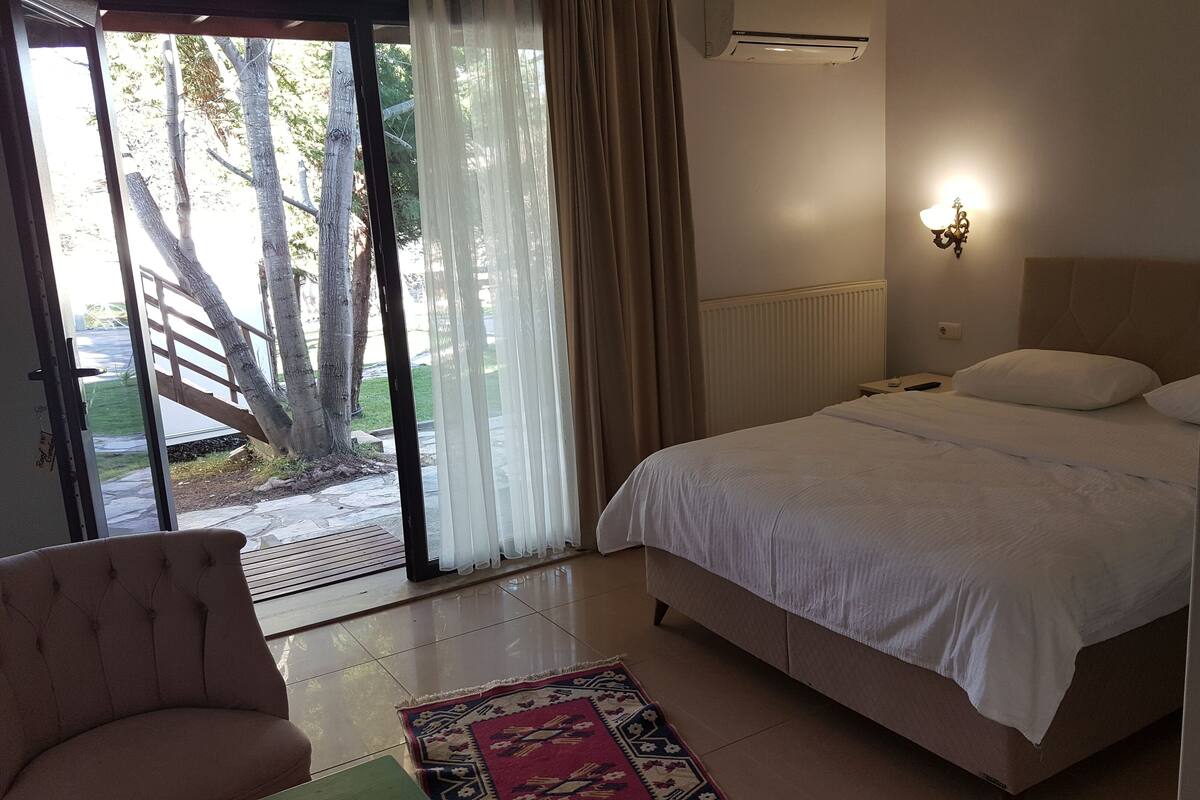 Un dormitorio con cama, una silla, ventana con cortinas y un radiador.