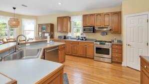Une cuisine moderne avec des meubles en bois, des appareils en acier inoxydable et un grand îlot central doté d’un évier.