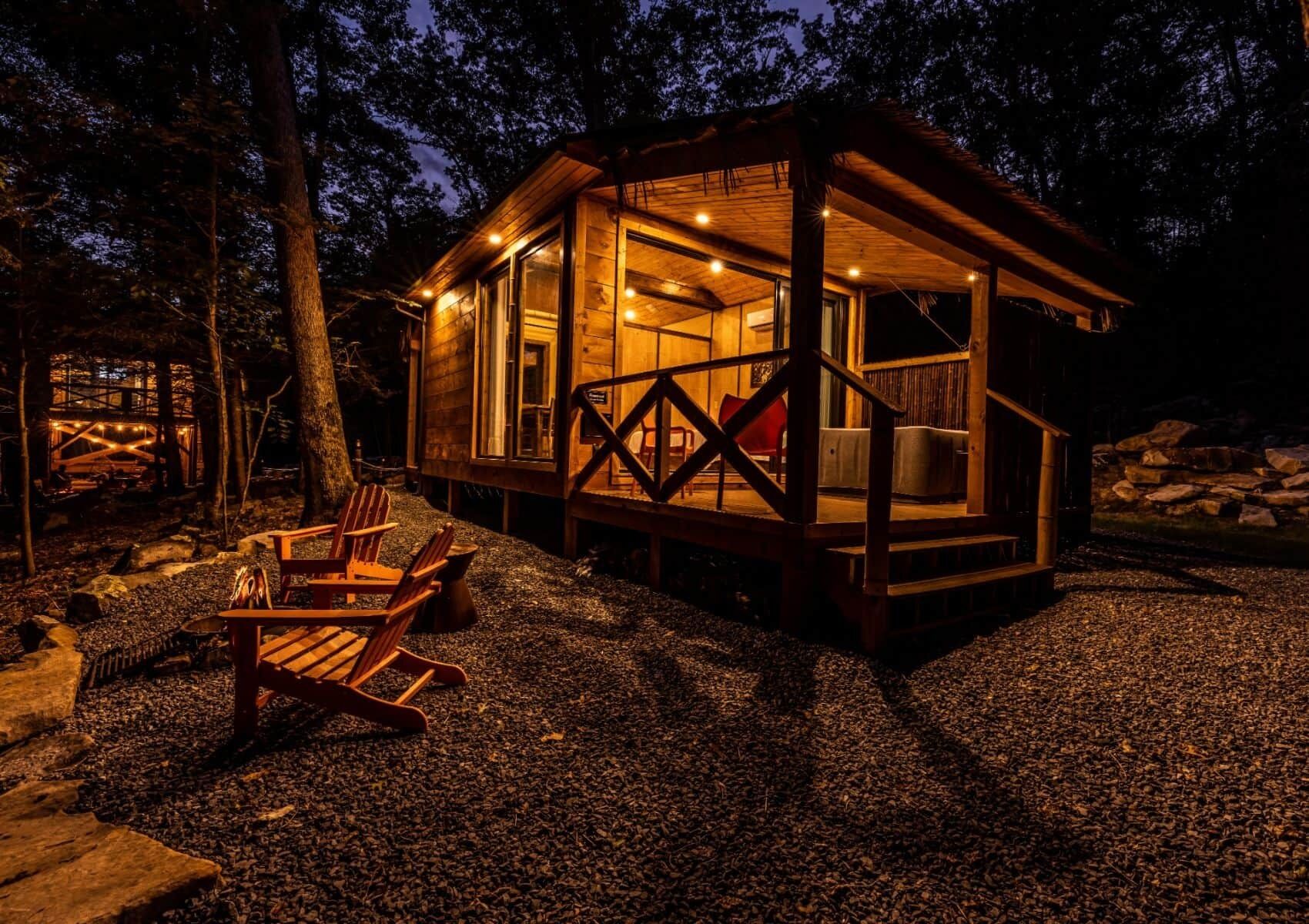 Une cabane en bois dotée d’une terrasse, d’un coin salon et d’une petite table.
