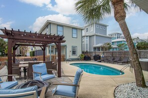 Un jardin avec une piscine, du mobilier d’extérieur et une pergola.