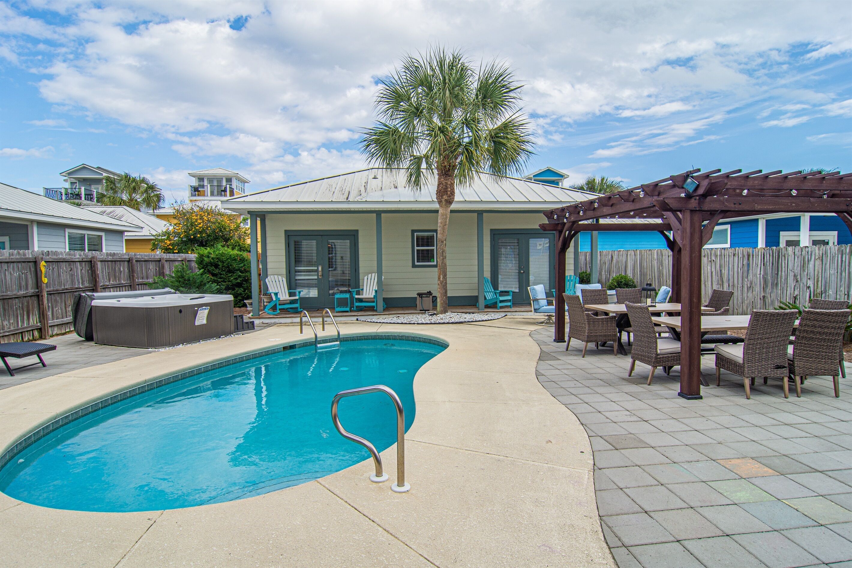 A backyard with a swimming pool, patio furniture, and a wooden pergola.