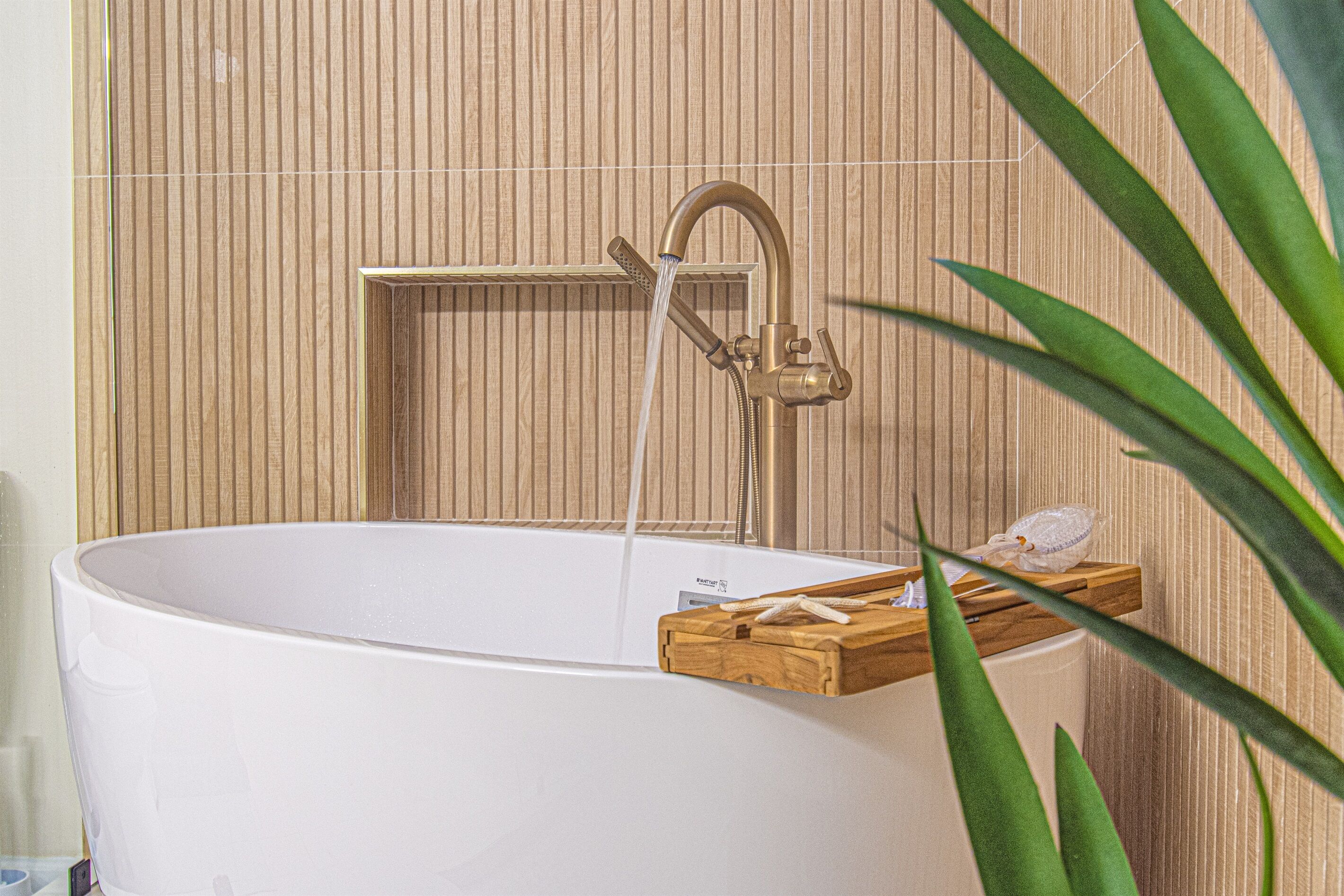 Une baignoire avec une étagère en bois, une pomme de douche et un porte-serviettes.