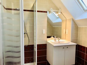 Een moderne badkamer met een douchecabine van glas, een wit wastafelmeubel en een spiegel erboven.