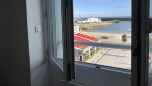 Blick aus einem Fenster auf ein Ufergebiet mit einer Mole, einem Restaurant und einer Fähre.