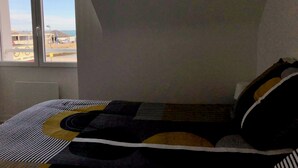 Ein Schlafzimmer mit Bett, Fenster und Blick nach draußen.