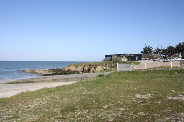 A coastal property with a modern building, a grassy area, and a view of the sea.