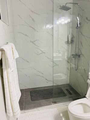 Une salle de bain moderne avec une douche à parois de verre, des toilettes et un porte-serviettes.