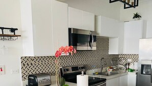 A modern kitchen with white cabinets, a wooden island, a microwave, a toaster, and a sink.
