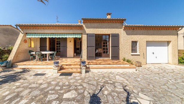 A two-story building with a tiled roof, a front door, and a garage. There is a patio with a table and chairs. - Charming house at the gateway to the Ardèche (Pont-Saint-Esprit)