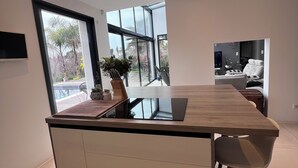 A modern kitchen with a central island, large windows, and a ceiling light fixture. - Modern villa full of sun for a great vacation (Biot)