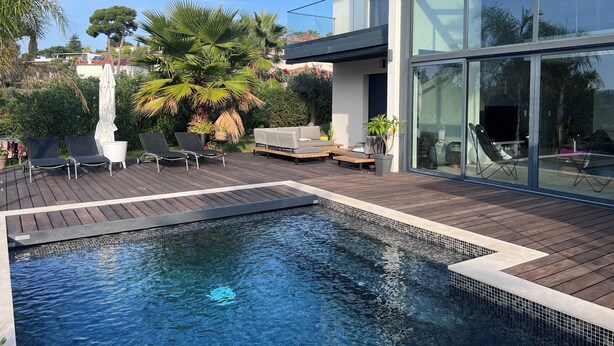 A modern outdoor pool area with lounge chairs and a wooden deck. - Modern villa full of sun for a great vacation (Biot)