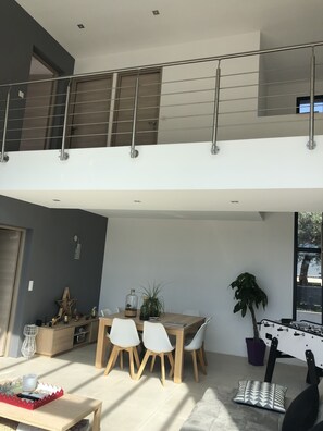 A modern, open-plan living area with a dining table, chairs, and a foosball table.
