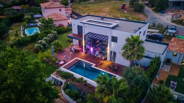 A modern house with a swimming pool, a patio, and a garden.
